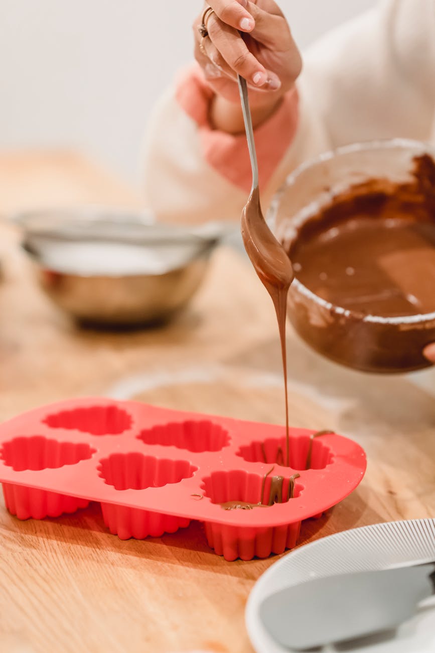 black woman pouring sweet tasty chocolate into silicone baking dish