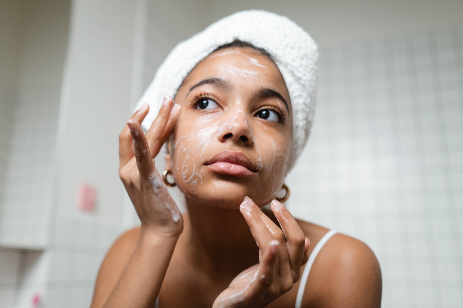 woman in white tank top washing her face with soap