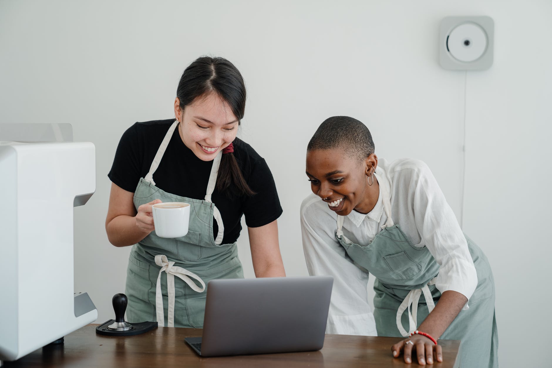 young female baristas watching funny video on laptop during break