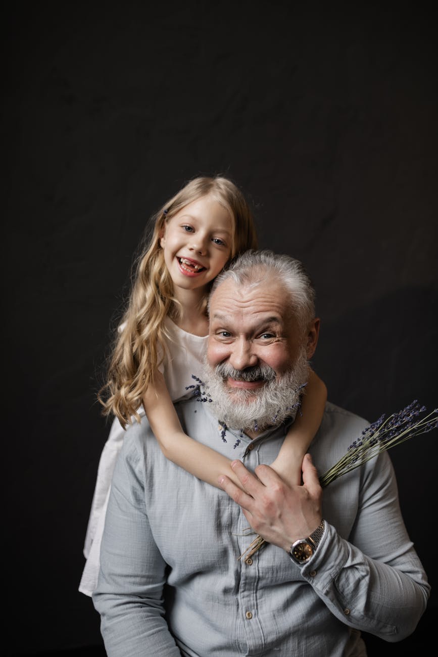 granddaughter hugging her grandfather while smiling